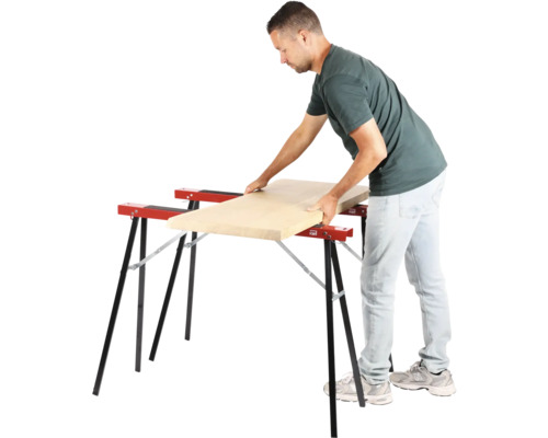 Mann legt Holzbrett auf zwei Arbeitsböcke