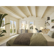 Innenansicht eines hellen Holzhauses mit Bett, Schreibtisch und Kommode