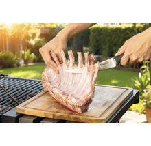 Zubereitung von Lammkarree auf einem Holzbrett mit einem Tenneker Messer im Garten.