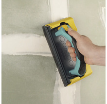 Handschleifer beim Schleifen einer Wand.