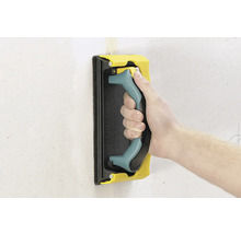 Hand mit Schleifigel zum Schleifen einer Wand