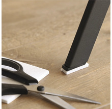 Stuhlbein mit Filzgleiter, Filzgleiter und Schere auf Holzboden