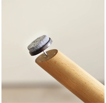 Filzgleiter mit Nagel an einem Möbelbein aus Holz