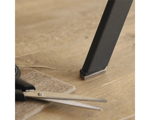 Stuhlbein mit Filzgleiter, Filzgleiter und Schere auf Boden