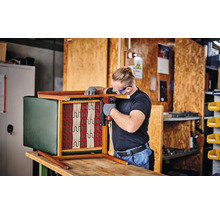 Ein Mann befestigt mit einem Druckluftnagler die Federung an einem Sessel.