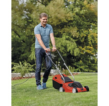 Ein Mann mäht den Rasen mit einem elektrischen Rasenmäher.