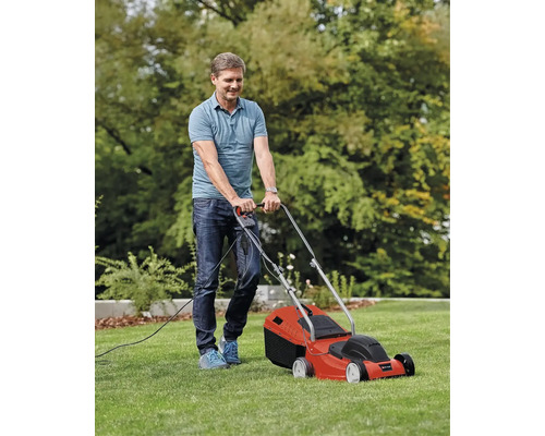 Ein Mann mäht den Rasen mit einem elektrischen Rasenmäher.