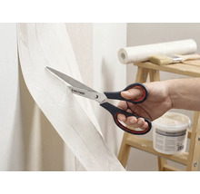 Eine Person schneidet Tapete mit einer Schere der Marke Rautner