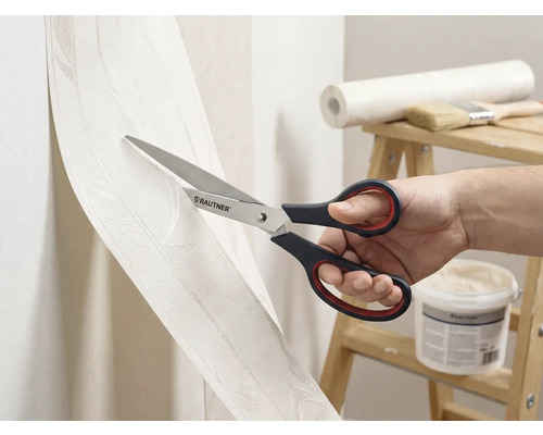 Eine Person schneidet Tapete mit einer Schere der Marke Rautner