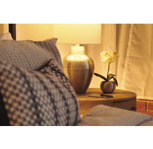 Nachttisch mit Lampe, Dekoration und Textilien in einem Schlafzimmer