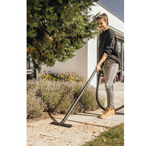 Frau saugt mit einem Nass Trockensauger Laub im Garten