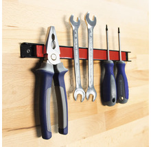 Werkzeuge wie Zange, Schraubenschlüssel und Schraubendreher an einer magnetischen Werkzeugleiste.