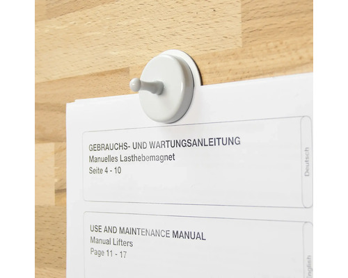 Magnetischer Haken hält eine Bedienungsanleitung an einer Holzoberfläche