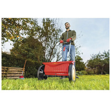 Eine Person bedient einen Düngerstreuer im Garten.