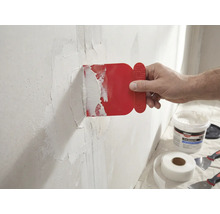 Ein Mann trägt eine rote Spachtel auf eine Wand mit Glasfaserklebeband auf