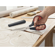 Tapetenschere schneidet Tapete auf einem Tisch.