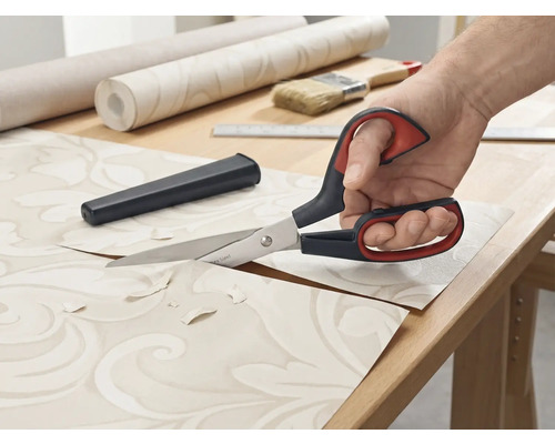 Tapetenschere schneidet Tapete auf einem Tisch.
