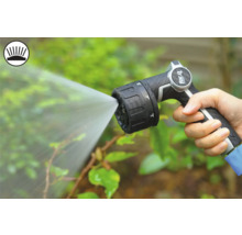 Eine Hand hält eine Gartenspritze, die Wasser versprüht