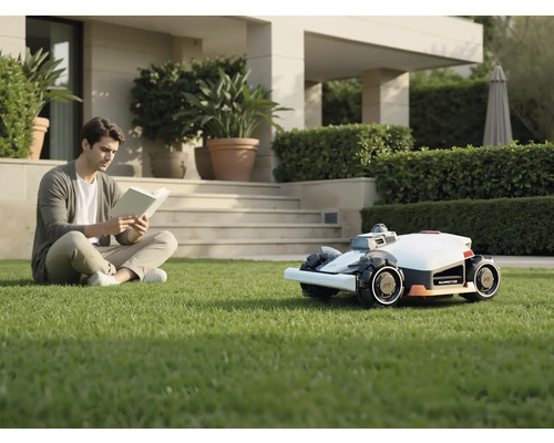 Mann liest Buch im Garten neben Mähroboter.
