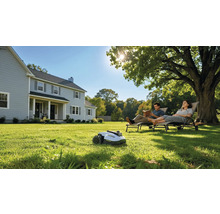 Szene mit Rasenmähroboter, Paar beim Entspannen im Garten und Wohnhaus