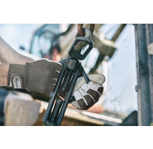 Nahaufnahme von Händen mit Arbeitshandschuhen, die einen Schraubstock bedienen