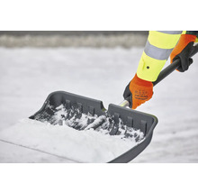 Person schippt Schnee mit einer Schneeschaufel