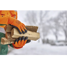 Person mit Arbeitshandschuhen, die Holzscheite trägt