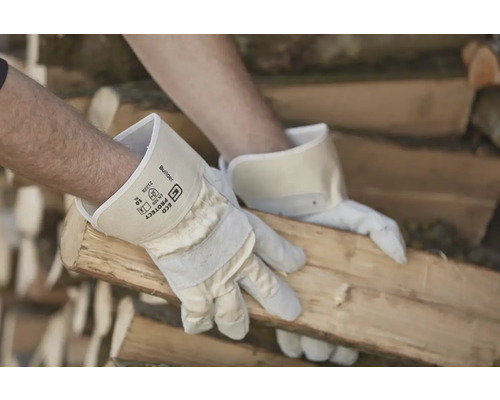 Ein Mann mit Arbeitshandschuhen hantiert mit Holz.
