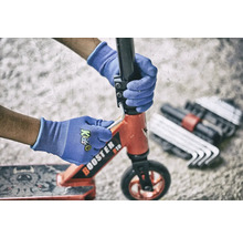 Eine Person repariert einen Tretroller mit Werkzeug und Schutzhandschuhen