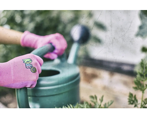 Hände mit Kinderhandschuhen halten eine Gießkanne
