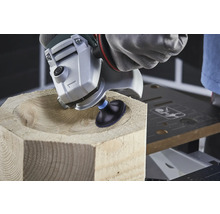 Eine Holzbearbeitung mit einem Winkelschleifer formt eine Schale in einem Holzblock.