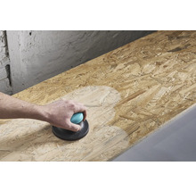 Eine Person schleift eine Holzplatte mit einem Handschleifer.