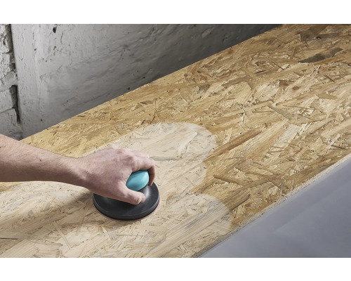 Eine Person schleift eine Holzplatte mit einem Handschleifer.