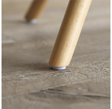 Nahaufnahme eines Stuhlbeins aus Holz mit Filzgleiter auf einem Holzboden