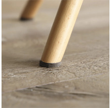 Detailansicht eines Stuhlbeins mit Filzgleiter auf Holzboden