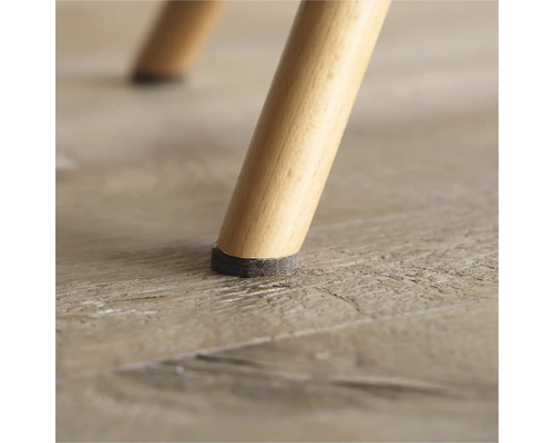 Detailansicht eines Stuhlbeins mit Filzgleiter auf Holzboden