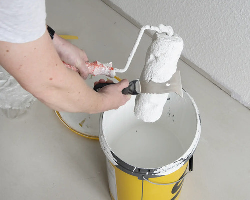 Farbeimer mit Farbroller und Abstreifgitter zum Streichen