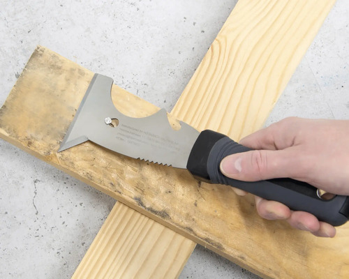 Mehrzweckspachtel mit Handgriff und Sägekante wird auf einem Holzbrett verwendet.