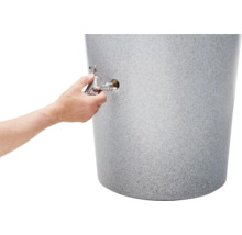 Eine Hand schraubt einen Auslaufhahn aus Metall in einen grauen Regenspeicher in Granitoptik.