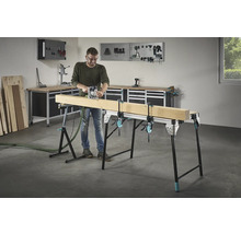 Mann fräst Holz auf einer Werkbank mit Schraubzwingen in einer Werkstatt