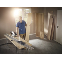 Mann mit Handkreissäge und Führungsschiene beim Holzzuschnitt für ein Regal