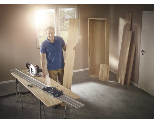 Mann mit Handkreissäge und Führungsschiene beim Holzzuschnitt für ein Regal