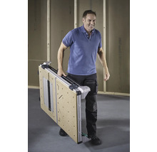 Ein Mann trägt einen zusammengeklappten Werktisch.