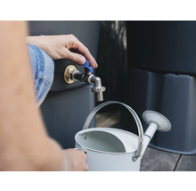 Person befüllt eine Gießkanne an einem Regenfasshahn