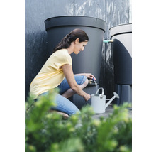 Frau befüllt Gießkanne mit Wasser aus einem Regenspeicher