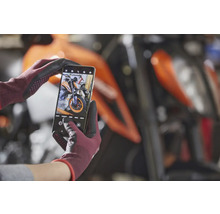 Ein Smartphone in behandschuhten Händen fotografiert ein Motorrad.
