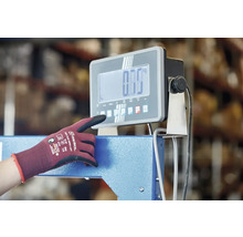 Eine Person bedient eine digitale Industriewaage mit einem Arbeitshandschuh