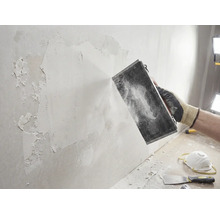 Handwerker schleift Wand mit Schleifwerkzeug. Heimwerkerprojekt zur Wandrenovierung.