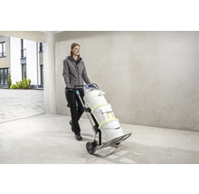 Frau transportiert Farbeimer mit einer Sackkarre.