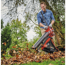 Ein Mann benutzt einen Laubsauger im Garten, um Laub zu entfernen.